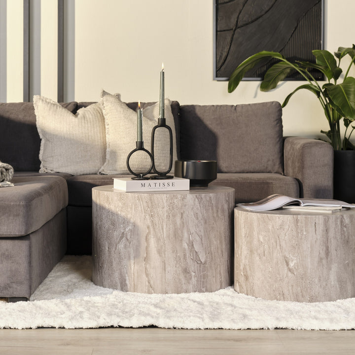 Dice sidebord i grå marmorlook foran gråbrun sofa med grønn plante og sort kunst