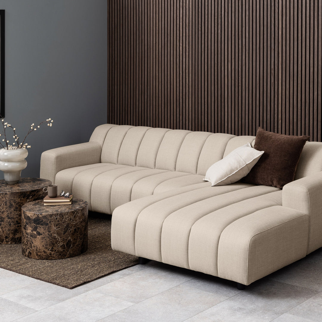 Dice sidebord i brun marmorlook foran beige bouclésofa med panelvegg