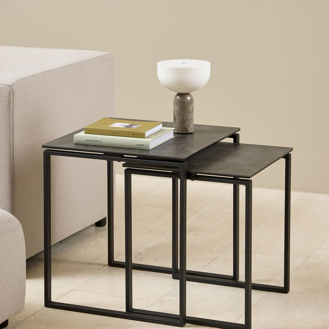 Katrine sidebord med sort keramikkplate og sort metallramme, sett med to bord ved lys sofa