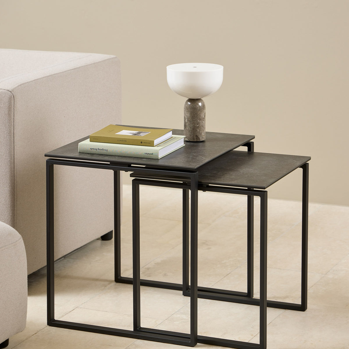 Katrine sidebord med sort keramikkplate og sort metallramme, sett med to bord ved lys sofa