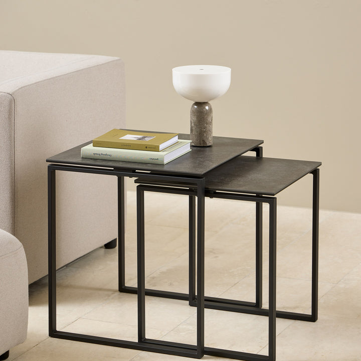 Katrine sidebord med sort keramikkplate og sort metallramme, sett med to bord ved lys sofa