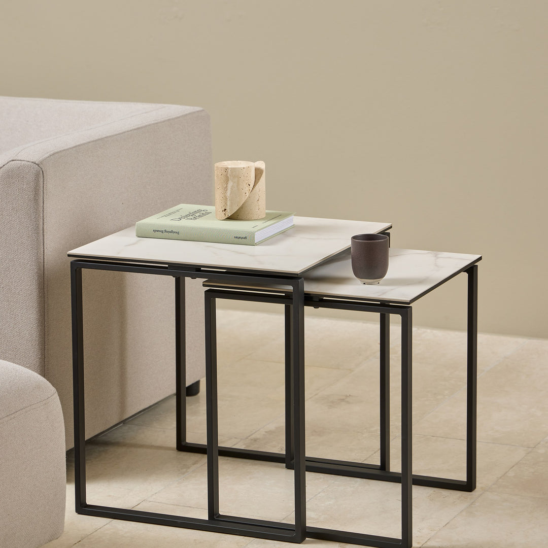 Katrine sidebord med hvit keramikkplate og sort ramme, sett med to bord ved beige sofa og puff