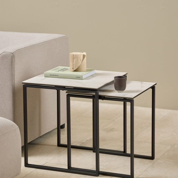 Katrine sidebord med hvit keramikkplate og sort ramme, sett med to bord ved beige sofa og puff
