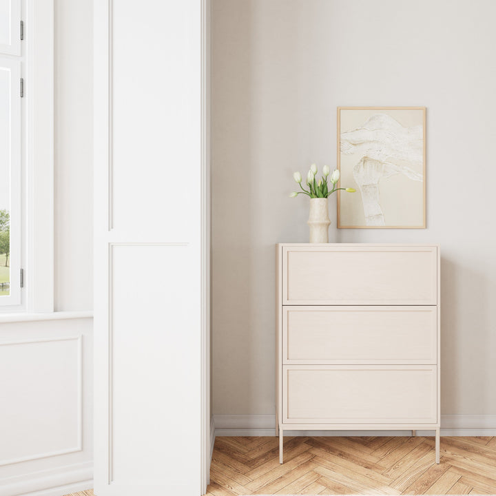 Palma kommode i lys krem, i hvitt rom med kunstplakat, vase med tulipaner og sildebensparkett