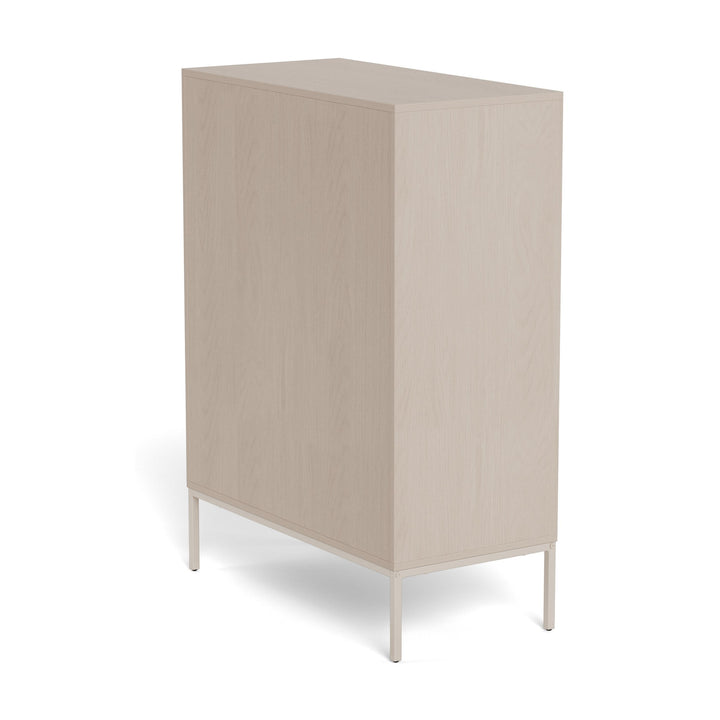 Palma kommode i lys greige sett bakfra på skrå, med beige metallunderstell