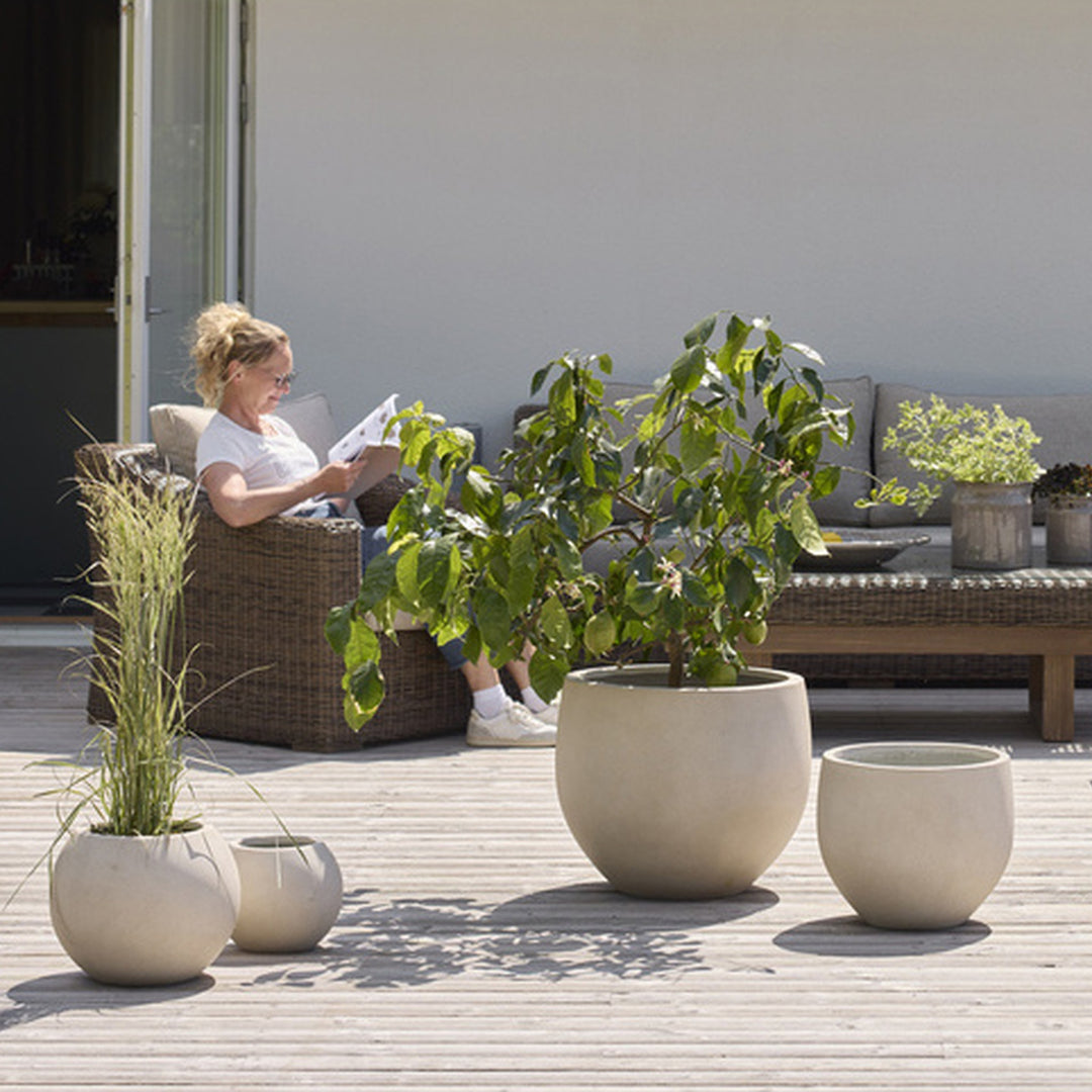 Phuc potte i offwhite, tre runde kulepotter med planter på en terrasse av tre