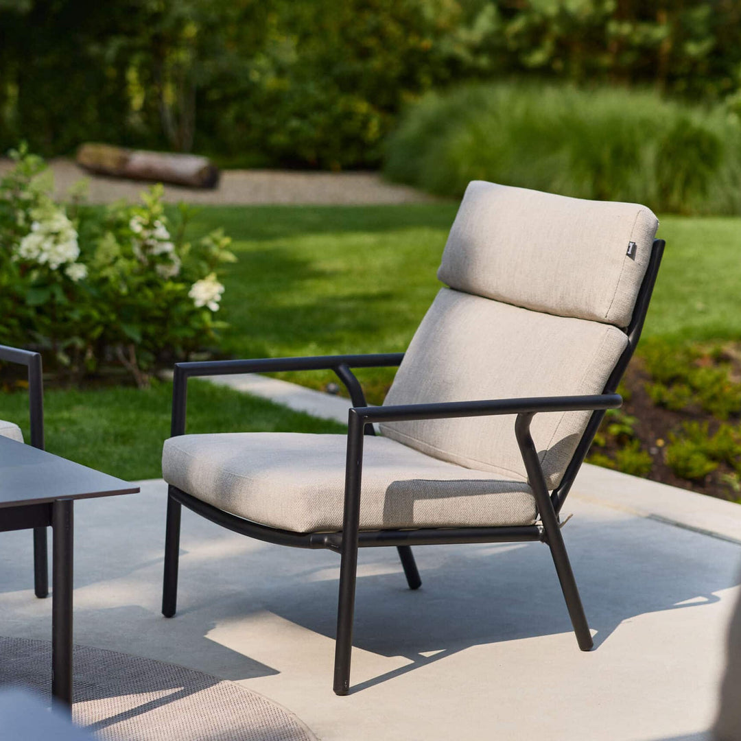Hartman Shinzo loungestol i sort med beige puter på terrasse ved grønn plen og hortensia