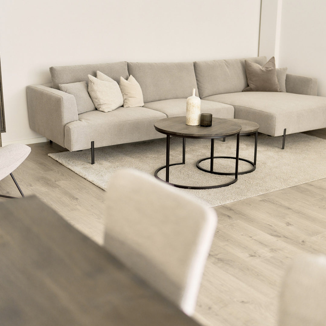 Milazzo hjørnesofa i lys beige stoff, høyrevendt sjeselong, i lys stue med rundt trebord