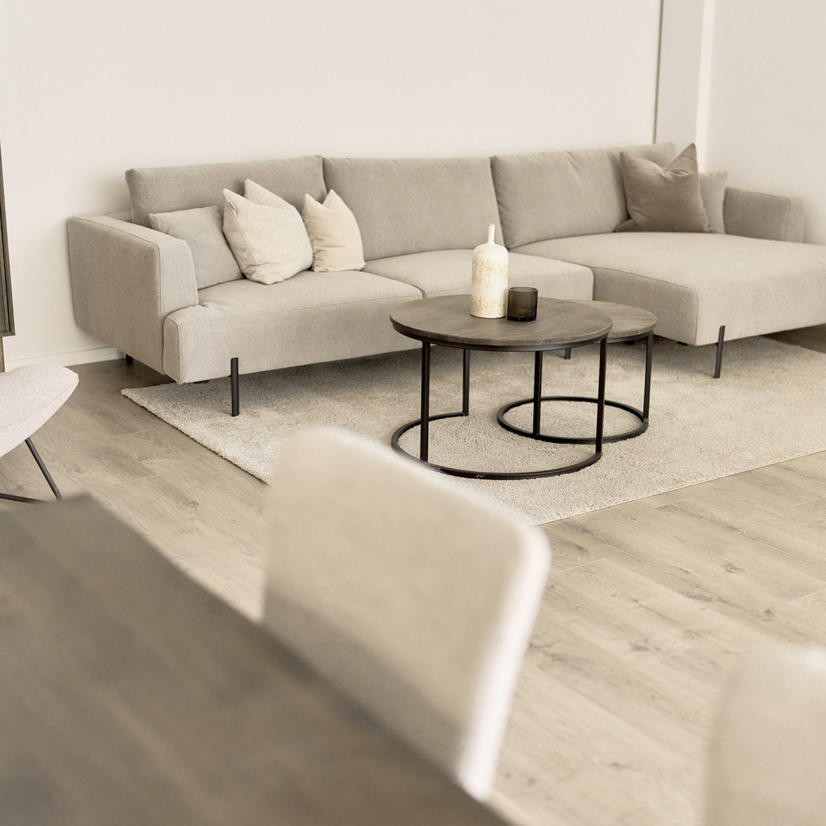 Milazzo hjørnesofa i lys beige stoff, høyrevendt sjeselong, i lys stue med rundt trebord