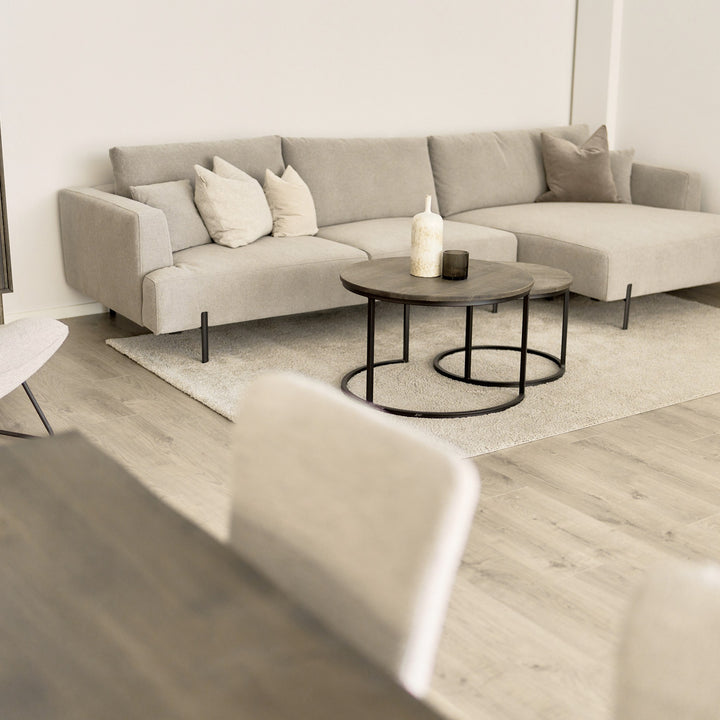 Milazzo hjørnesofa i lys beige stoff, høyrevendt sjeselong, i lys stue med rundt trebord