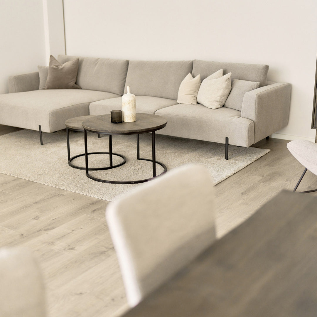Milazzo hjørnesofa i lys beige stoff, venstrevendt sjeselong, i lys stue med rundt trebord