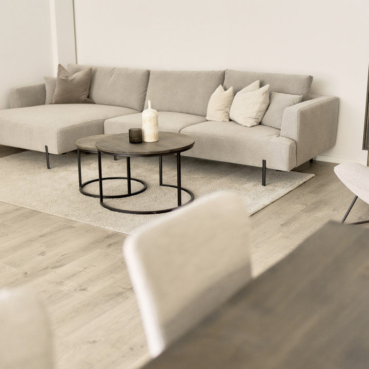 Milazzo hjørnesofa i lys beige stoff, venstrevendt sjeselong, i lys stue med rundt trebord