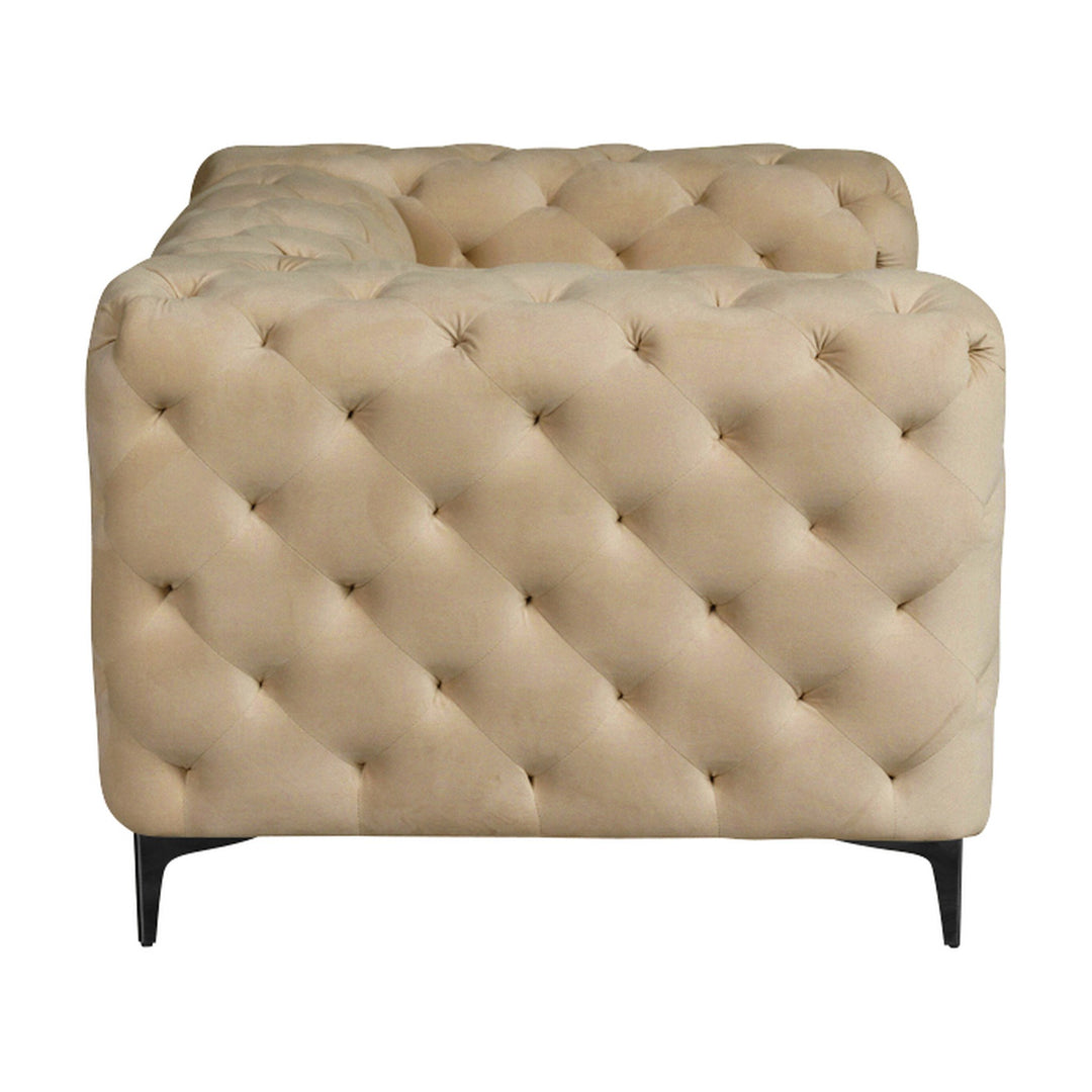 Bella sofa i beige velur, dyptuftet chesterfield-lenestol sett fra siden