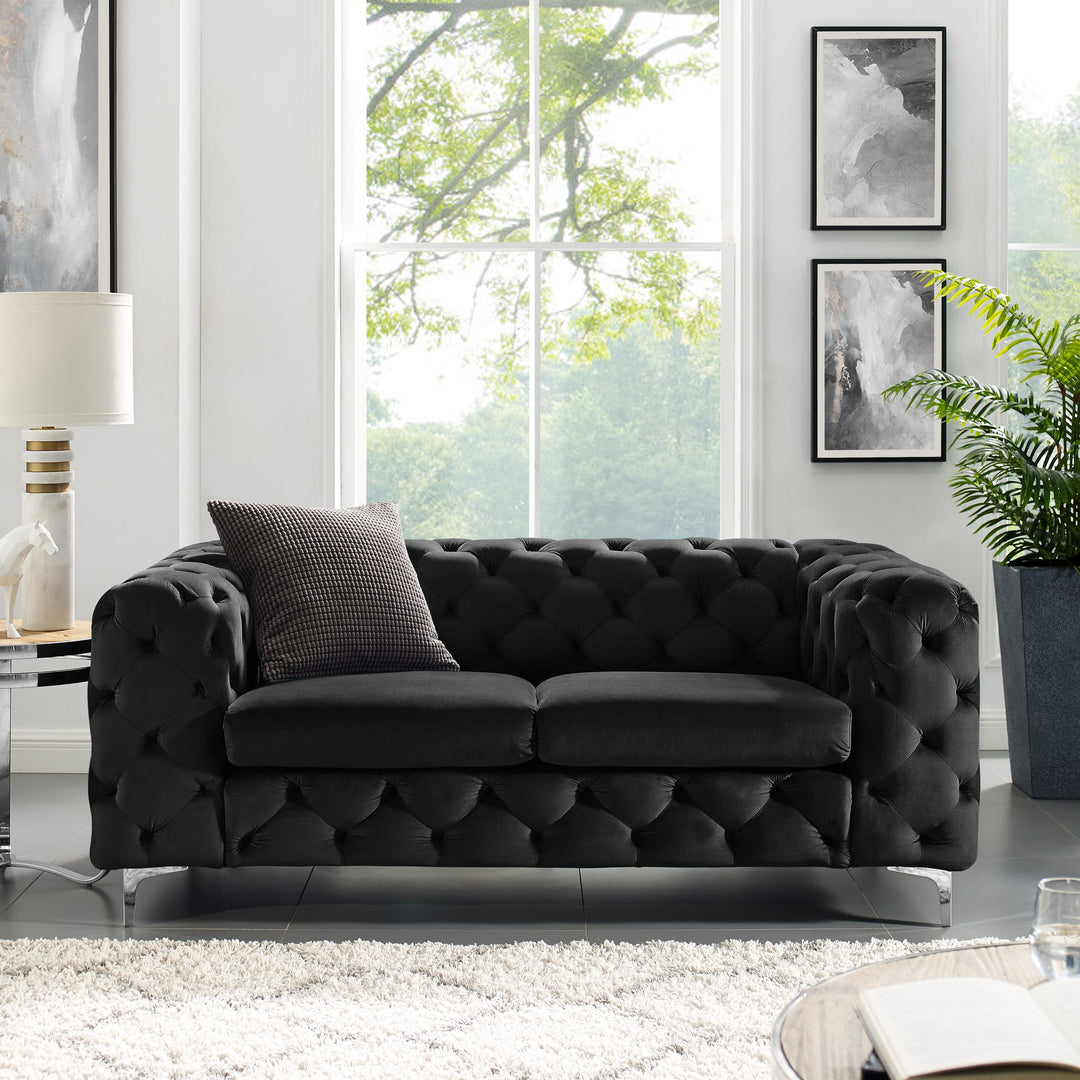 Bella sofa i sort velur, toseter i lys stue med grønn plante, lampe og mønstret pute