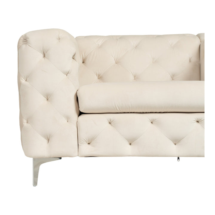 Bella sofa i kremhvit tuftet velur med krombein, nærbilde av hjørne mot hvit bakgrunn.