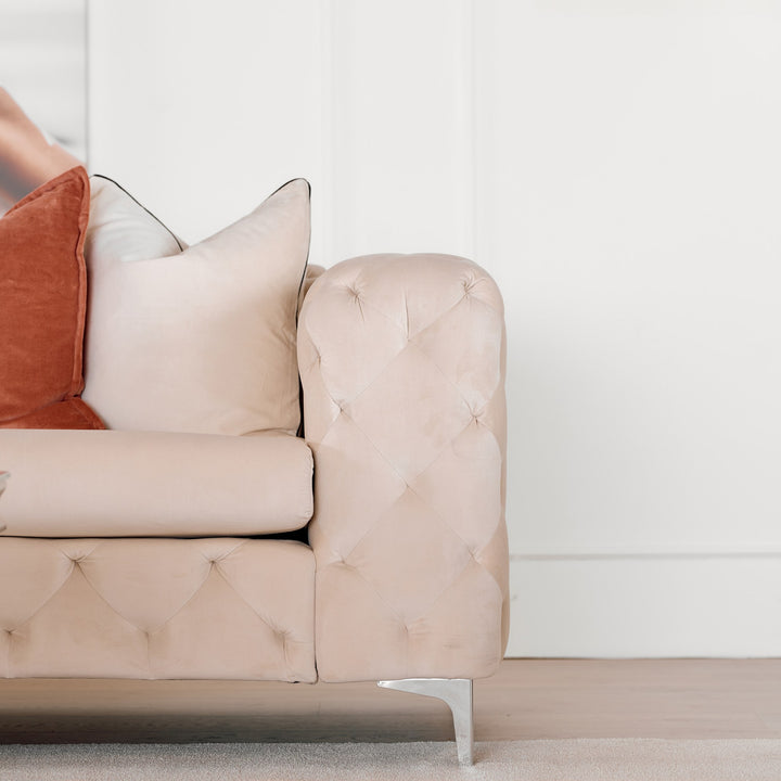 Bella sofa i krem velur, nærbilde av tuftet armlene med terrakotta og rosa puter og krombein