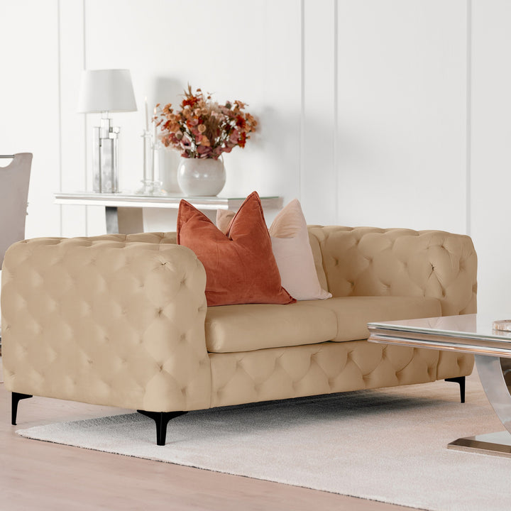 Bella sofa i beige velur, toseter i lys stue med terrakotta puter, konsollbord og blomster