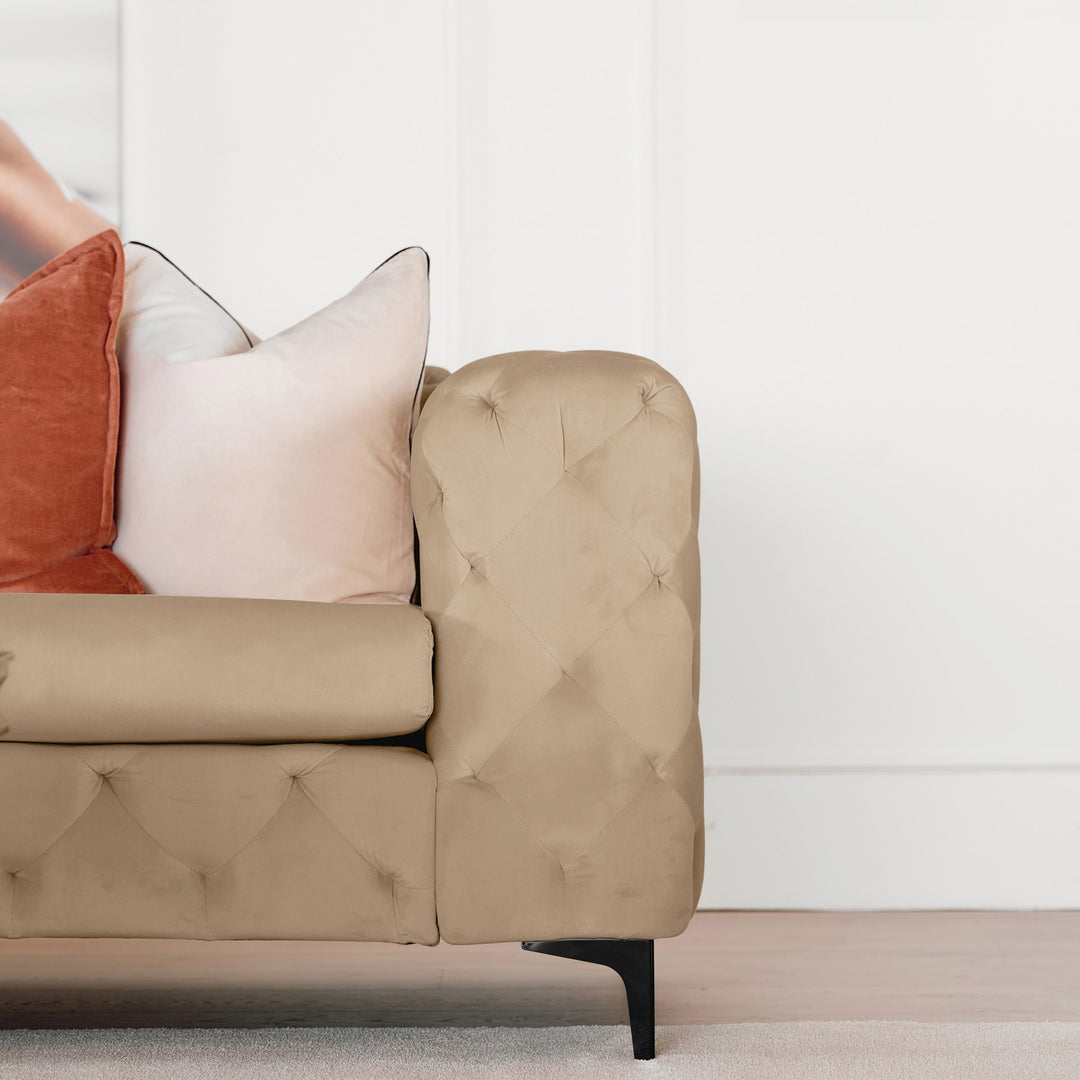 Bella sofa i beige velur, nærbilde av tuftet armlene med terrakotta og rosa puter og sort ben