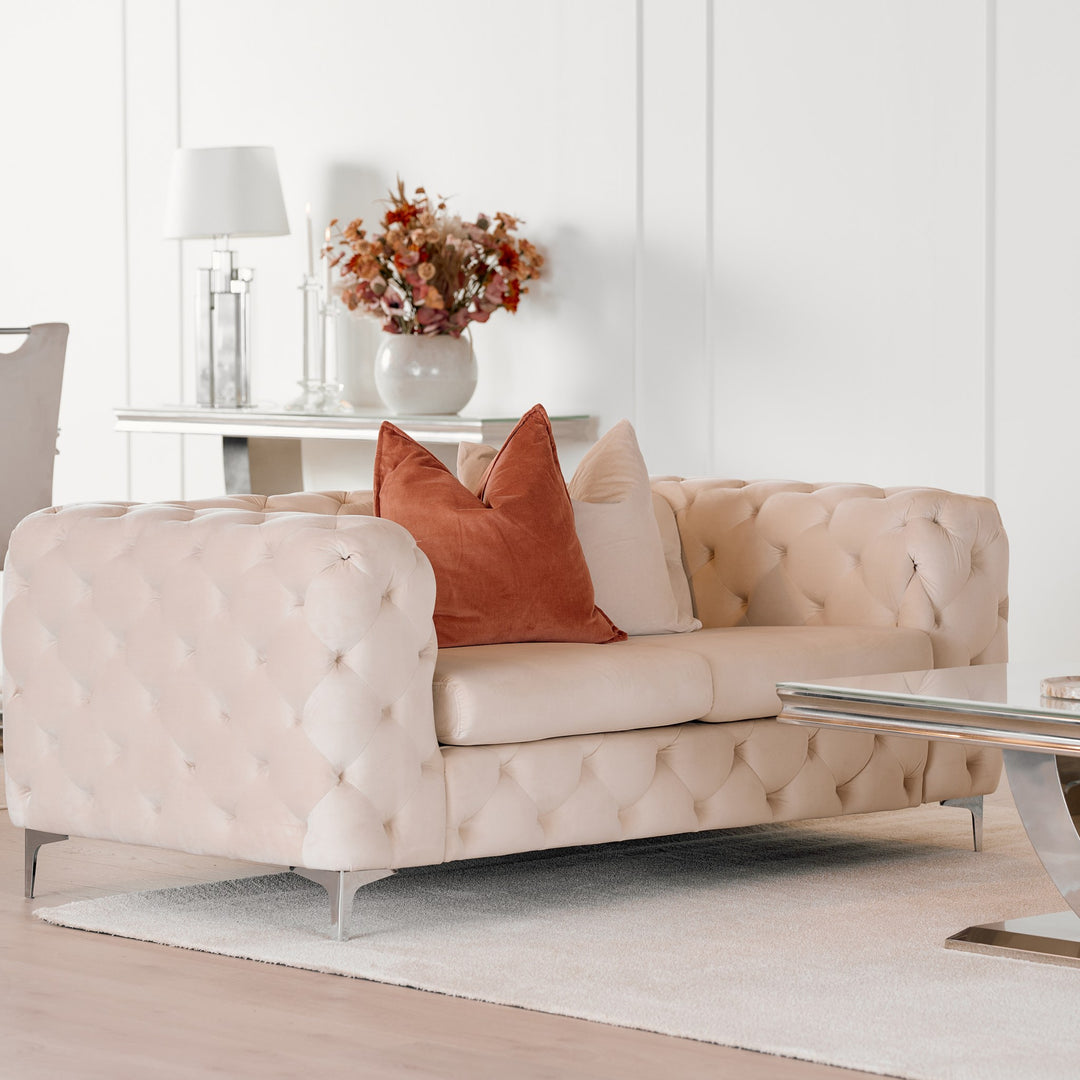 Bella sofa i krem velur, treseter i lys stue med terrakotta puter, konsollbord og blomster