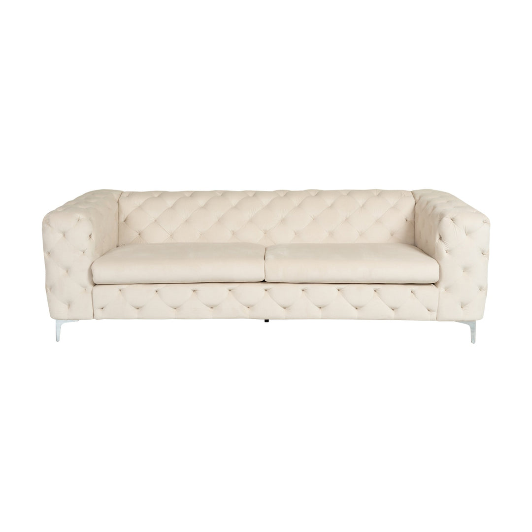 Bella sofa i krem velur, treseter med dyp knapptufting og blanke krombein, sett forfra