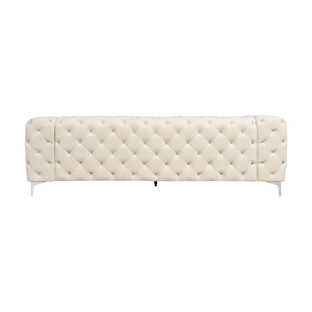 Bella sofa i kremhvit tuftet velur med krombein, sett forfra mot hvit bakgrunn.