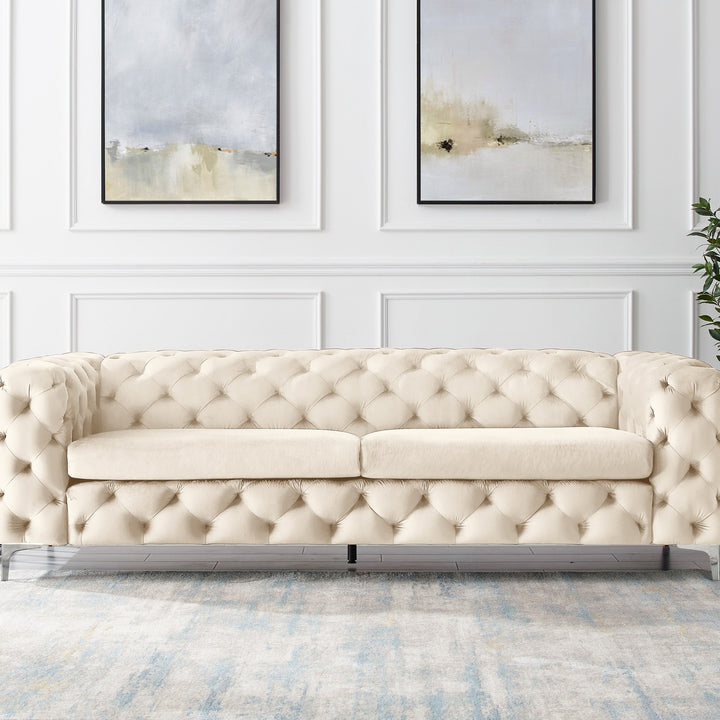 Bella sofa i krem velur, treseter i panelt stue med to abstrakte veggbilder og grønn plante