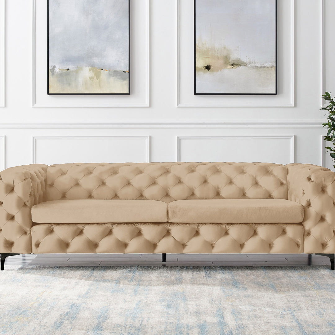 Bella sofa i beige velur, treseter med sorte ben i panelt stue med abstrakte veggbilder