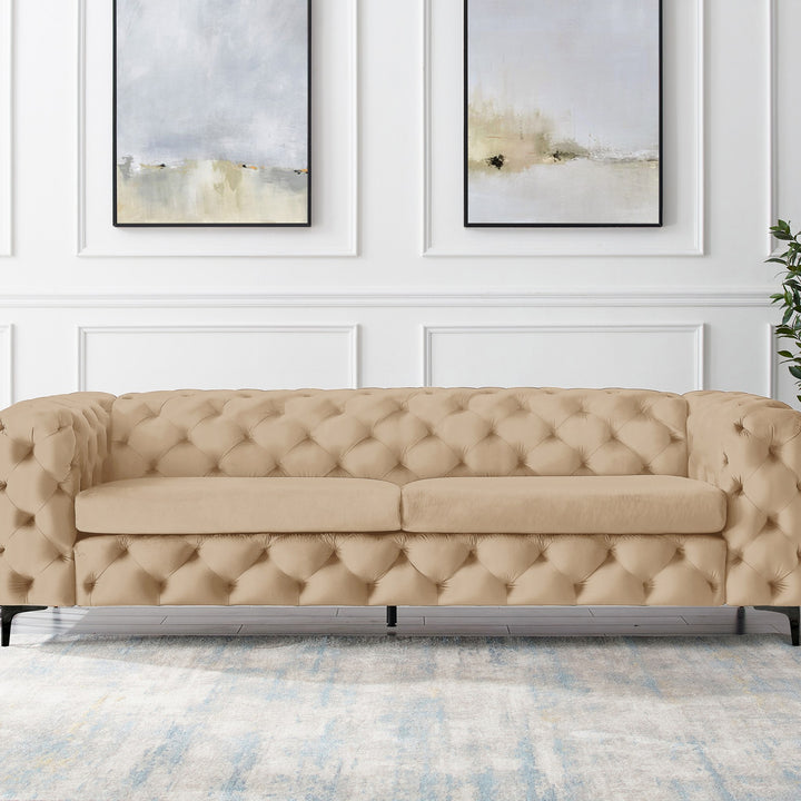 Bella sofa i beige velur, treseter med sorte ben i panelt stue med abstrakte veggbilder