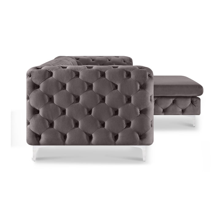 Bella hjørnesofa i grå tuftet velur med sjeselong og akrylben, sett fra siden mot hvit bakgrunn.