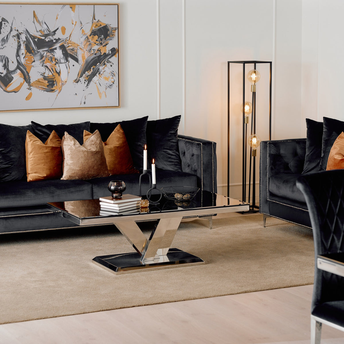 Dallas sofa i sort velur med knappetrekk, terrakotta og sorte puter, i stue med speilbord og abstrakt bilde