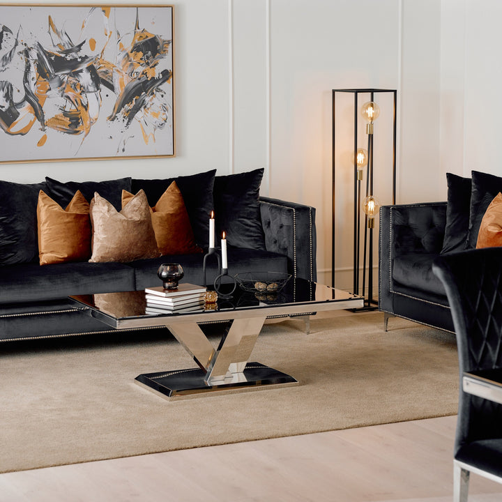 Dallas sofa i sort velur med knappetrekk, terrakotta og sorte puter, i stue med speilbord og abstrakt bilde