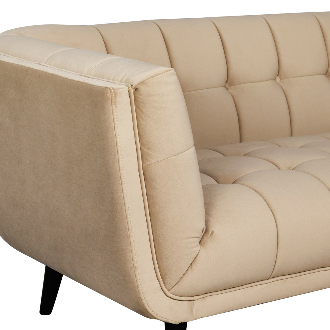 Simon sofa i beige velur, nærbilde av armlene og rutetuftet sete.