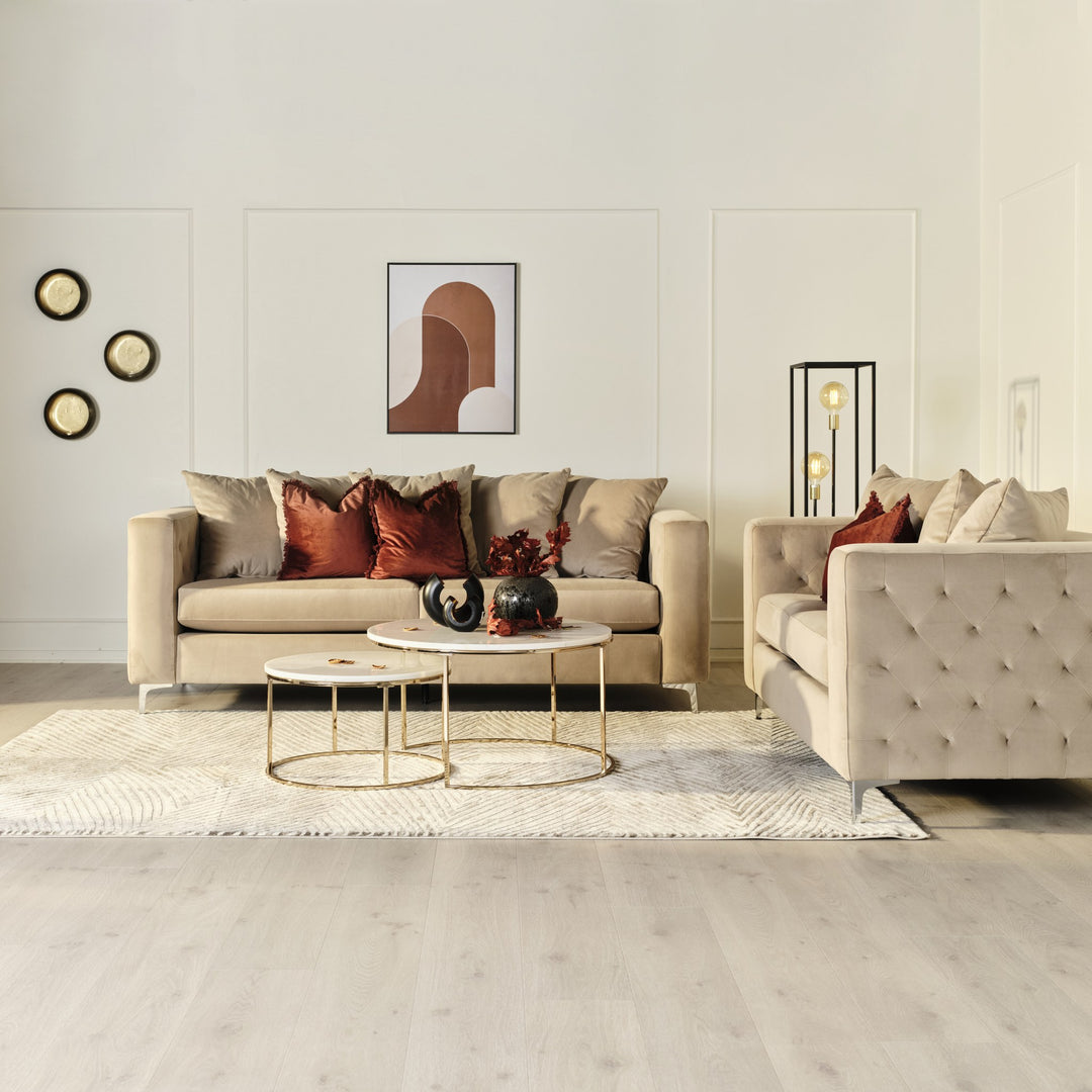 Boston sofa i beige velur med rutetuftede sider og krombein, i lys stue med rustrøde puter.