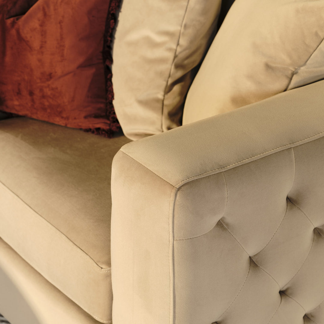 Boston sofa i beige velur, nærbilde av rutetuftet armlene med rustrød og beige pute.