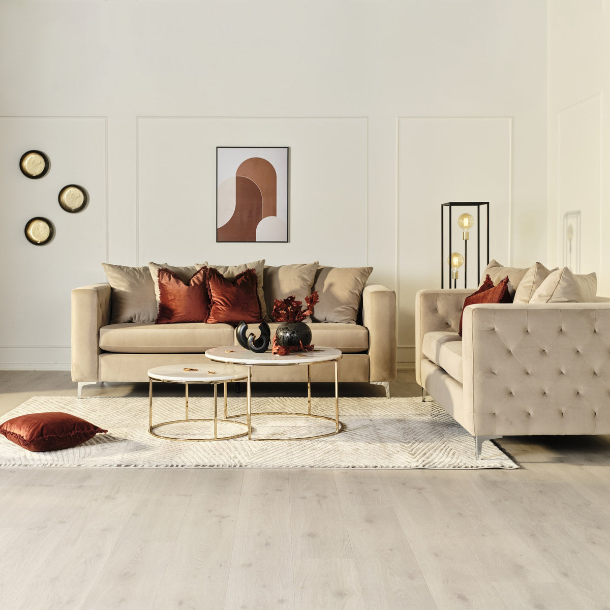 Boston sofa i beige velur, i lys stue med panelvegg, marmor sofabord og rustrød gulvpute