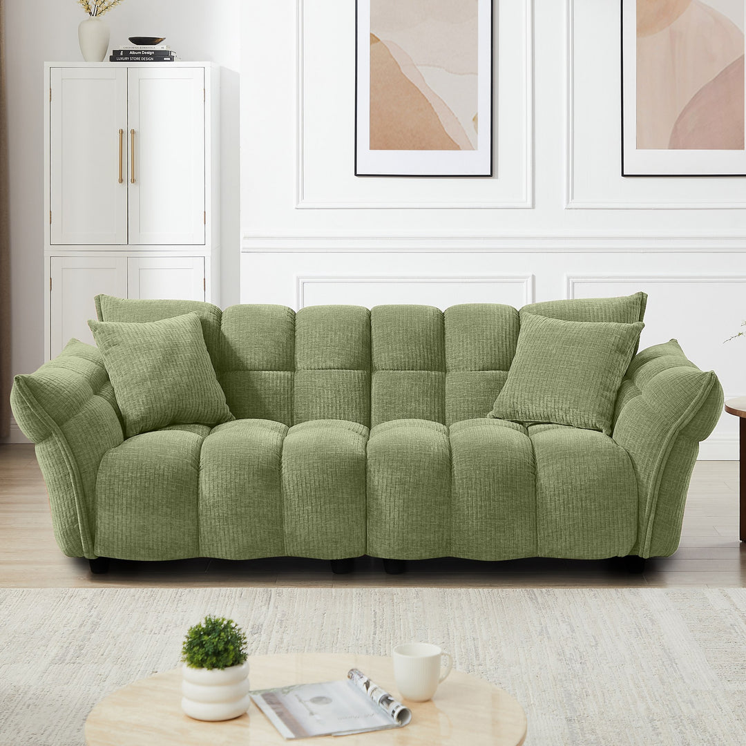Marigold sofa i grønn kordfløyel i lyst stuemiljø med hvitt skap og abstrakte veggbilder
