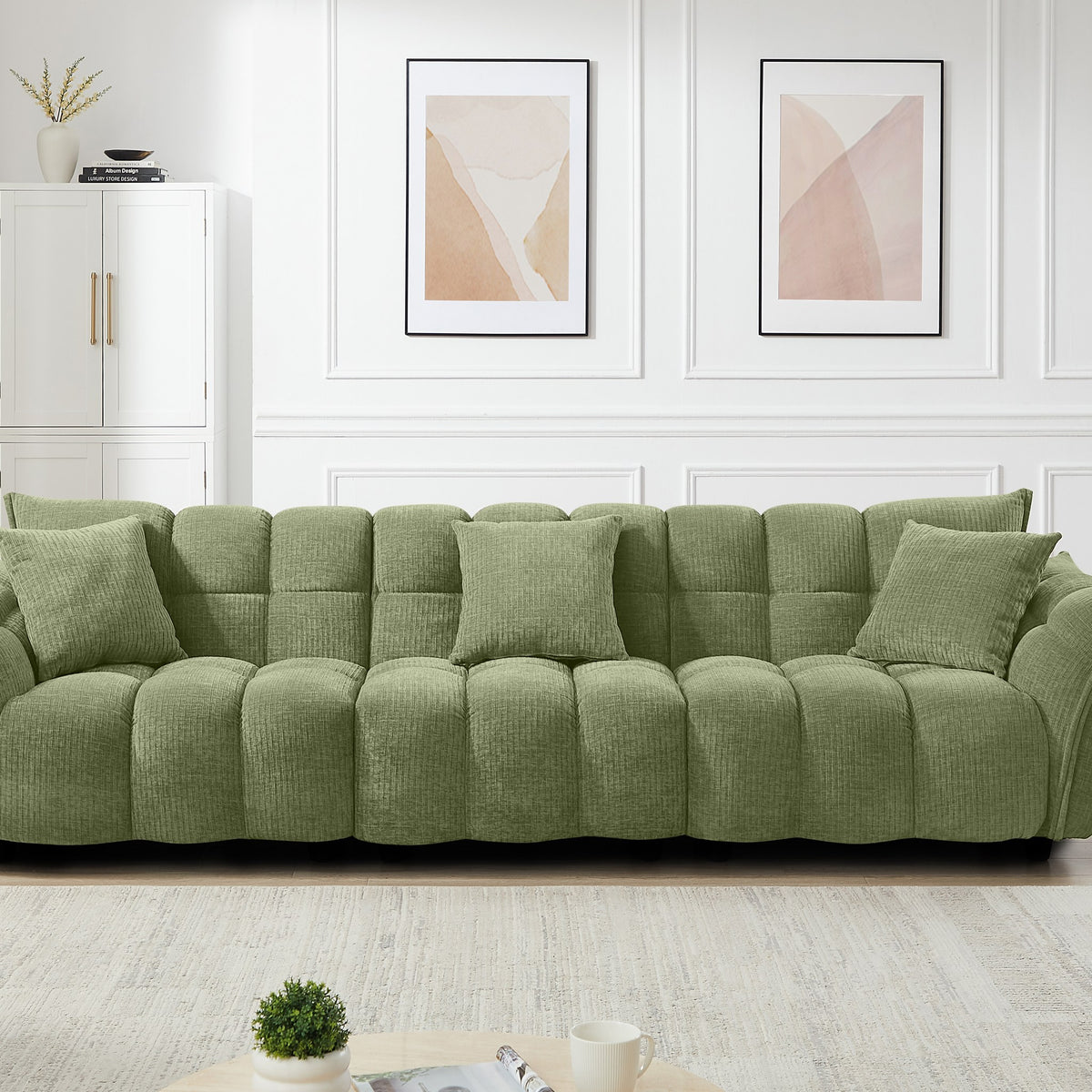 Marigold sofa i grønn kordfløyel, bred modell i stue med hvitt skap og abstrakte plakater