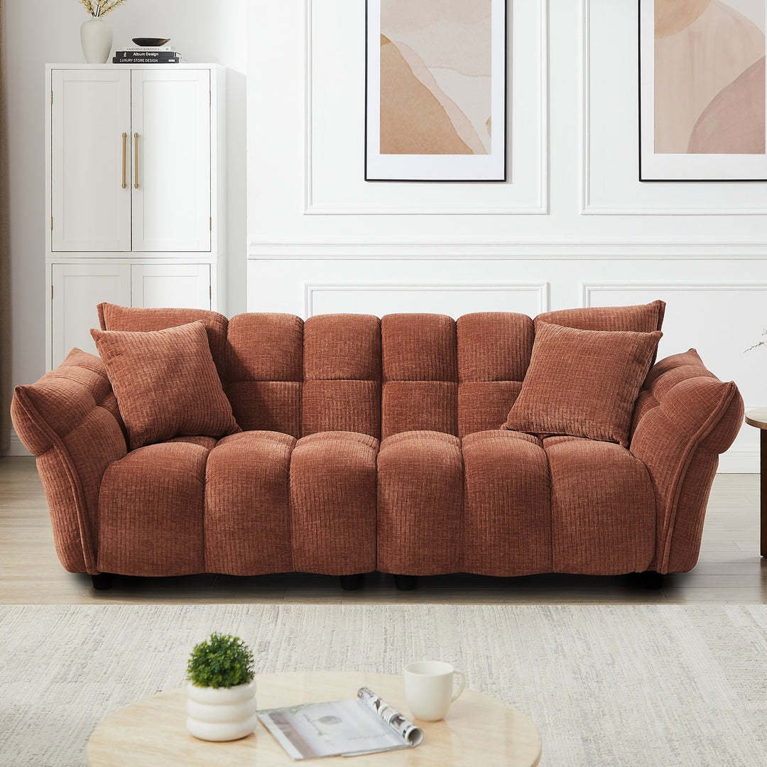 Marigold sofa i terrakotta kordfløyel i lyst stuemiljø med skap og abstrakte veggbilder