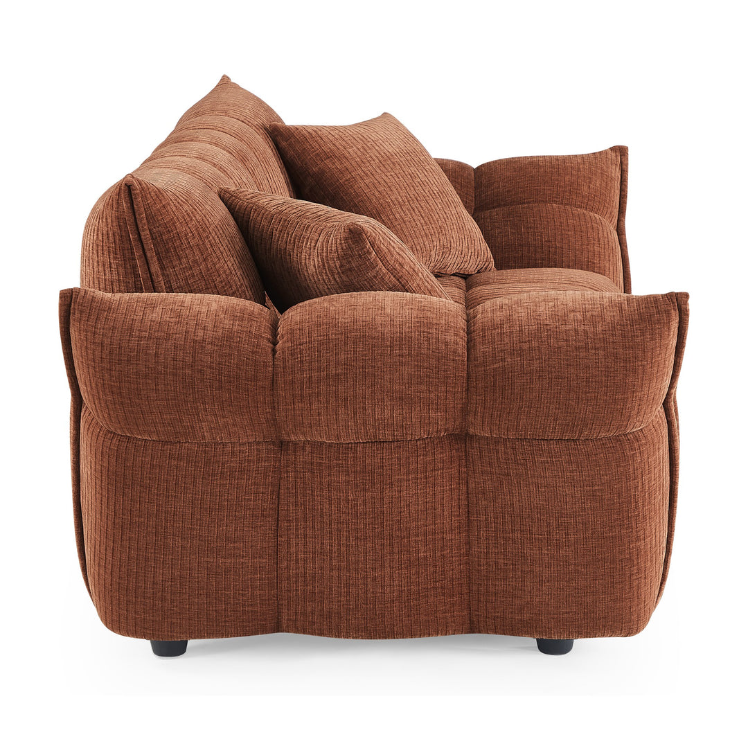 Marigold sofa i rustrødt sett fra siden, med puffet, ribbet design og mørke ben.
