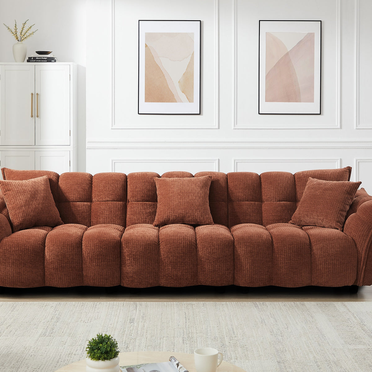 Marigold sofa i terrakotta kordfløyel, bred modell i stue med hvitt skap og bilder