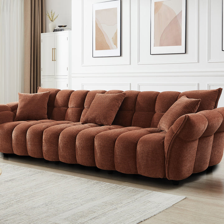 Marigold sofa i terrakotta kordfløyel i lyst stuemiljø med skap, veggbilder og teppe