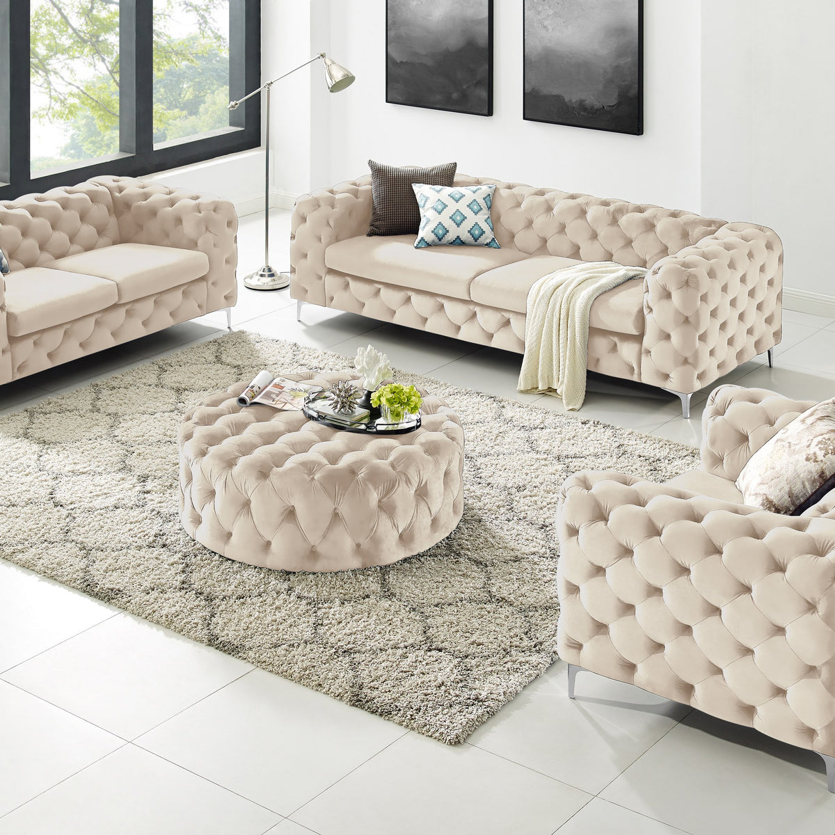 Bella puff i beige velur med knappetufting, rund modell i stue med chesterfieldsofaer