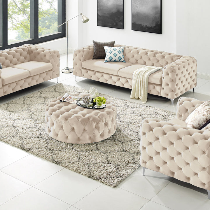 Bella puff i beige velur med knappetufting, rund modell i stue med chesterfieldsofaer