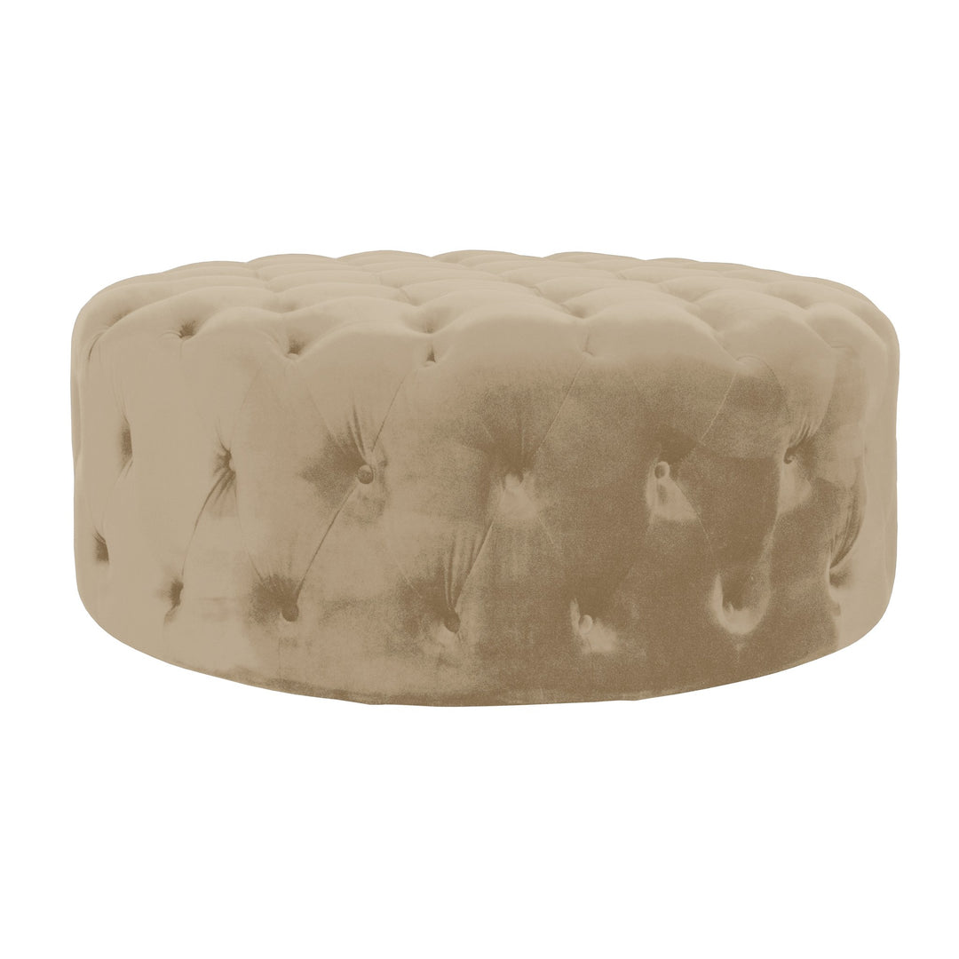 Bella puff i beige velur, rund med dyp knappetufting mot hvit bakgrunn.