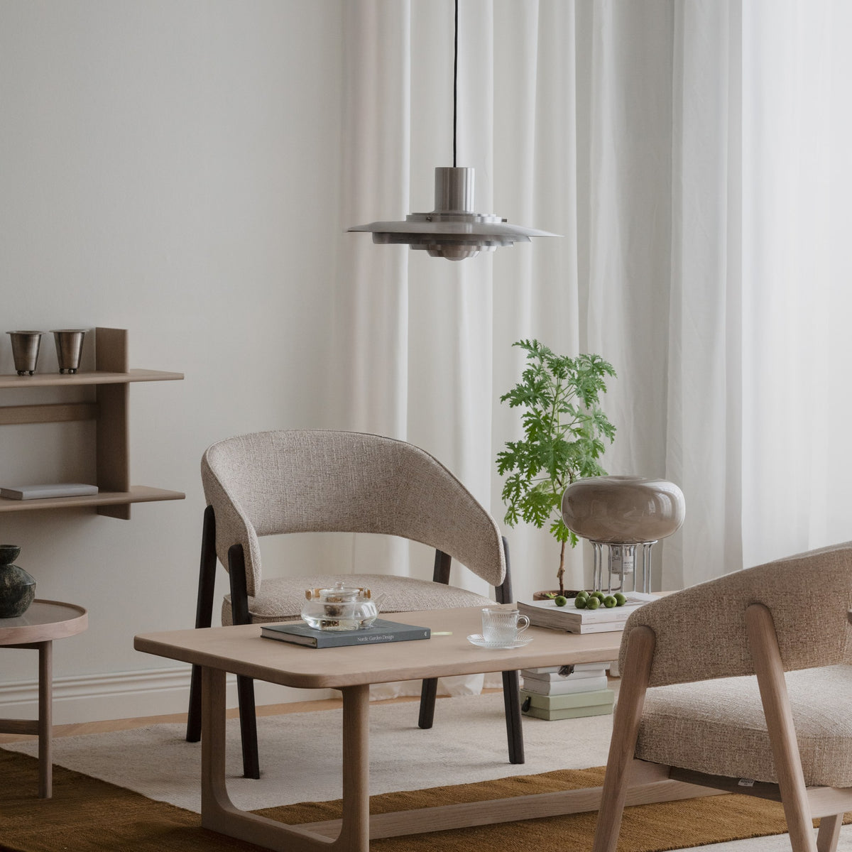 Rowico Barnaby loungestol i beige bouclé, i lyst rom med eikebord og pendel