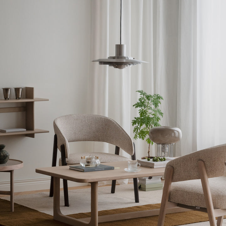 Rowico Barnaby loungestol i beige bouclé, i lyst rom med eikebord og pendel