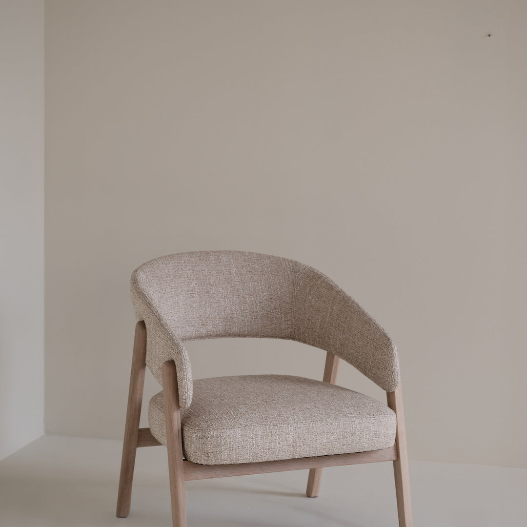 Rowico Barnaby loungestol i beige melert stoff og lys eikeramme, plassert i et lyst, beige rom