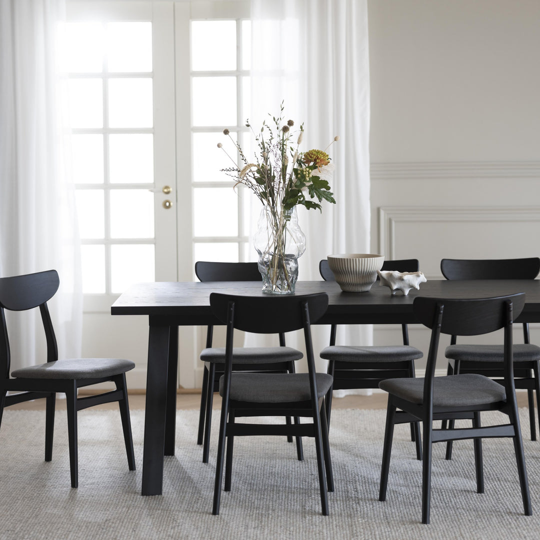 Rowico Winnipeg spisebord i sort eik med sorte stoler og blomsterbukett i lyst rom