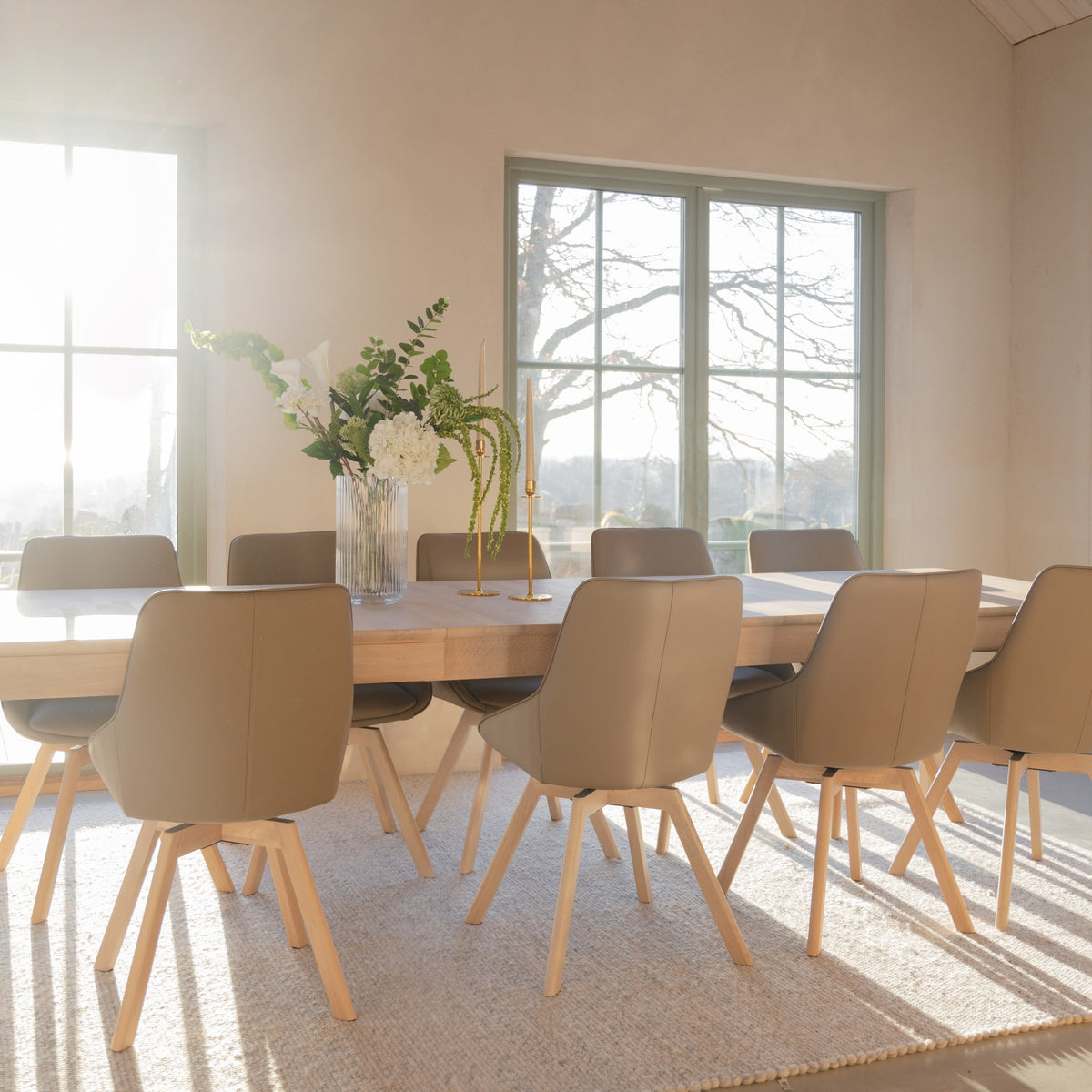 Rowico Gardner spisebord i hvitpigmentert eik med beige stoler, blomster og sollys i spisestue