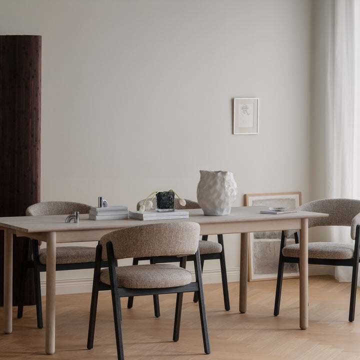 Rowico Derrymore spisebord i lys eik med beige stoler og hvit vase i lyst spiserom